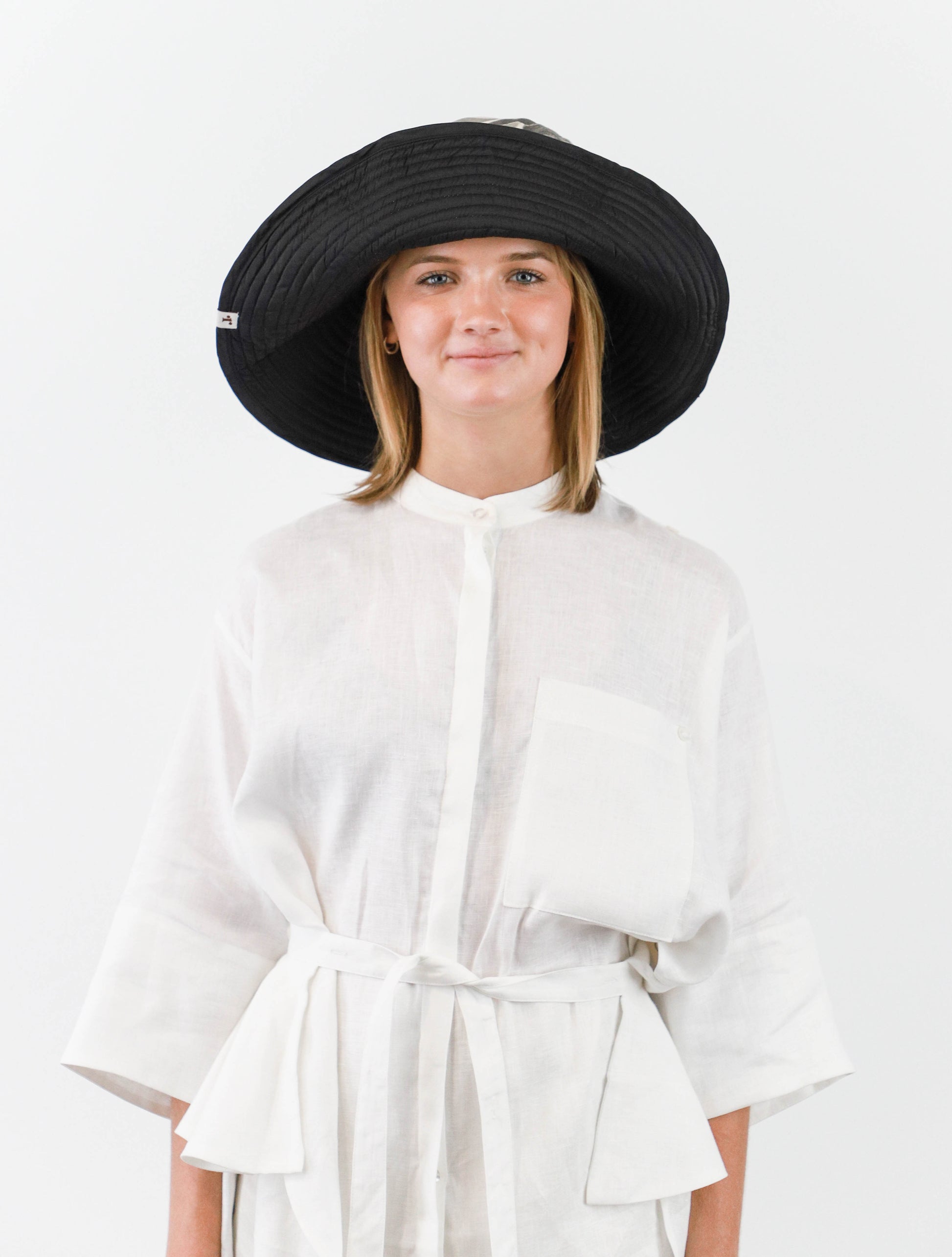 Romualda Roca bucket hat with black and white swirl pattern and black lining shown on model with brim folded up